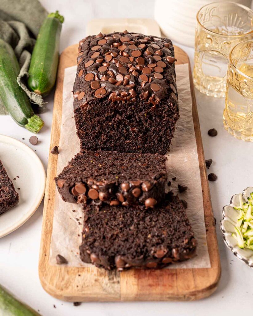 Chocolate zucchini bread with lots of chocolate chips on top and a rich fluffy texture. Bread has two slices cut off.