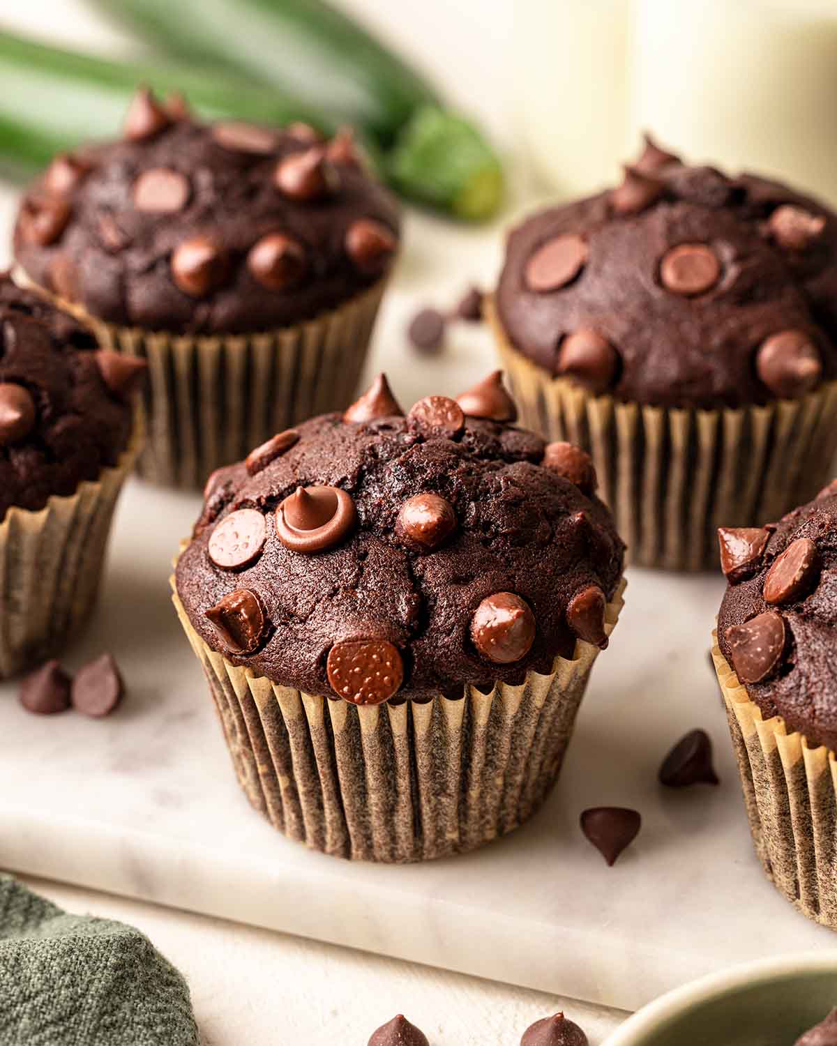 A few chocolate muffins on marble serving board, surrounded with chocolate chips.