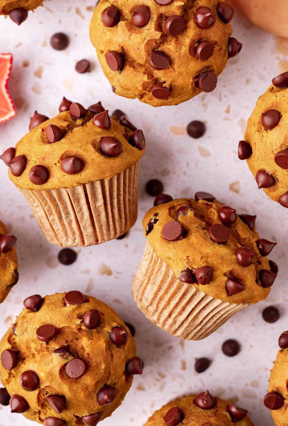 Overhead image of pumpkin muffins, with two muffins on their side showing the tall muffin tops.