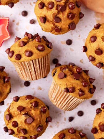 Overhead image of pumpkin muffins, with two muffins on their side showing the tall muffin tops.