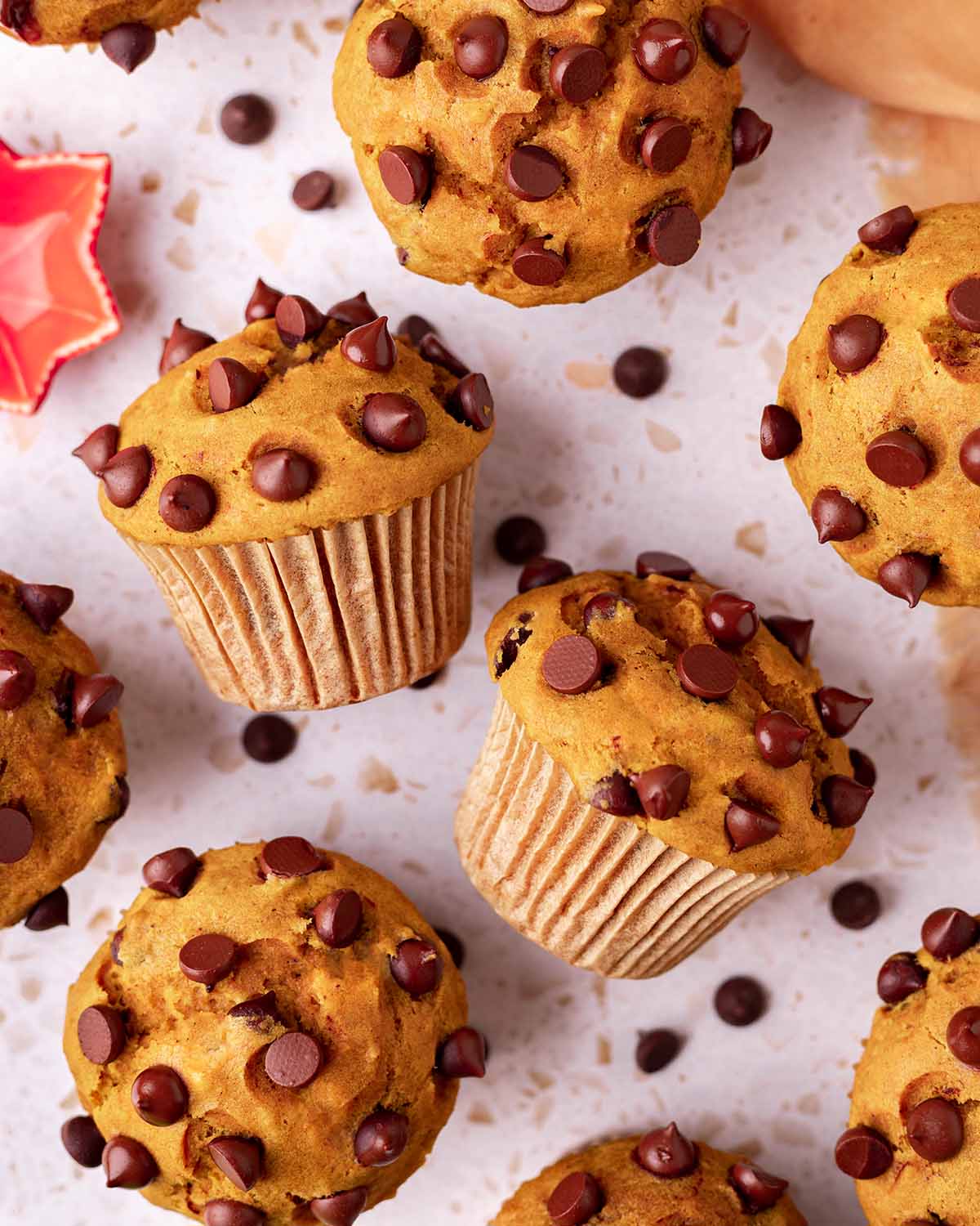 Overhead image of pumpkin muffins, with two muffins on their side showing the tall muffin tops.