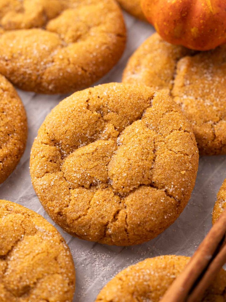 Close up of vegan pumpkin cookie amongst other cookies on parchment paper.