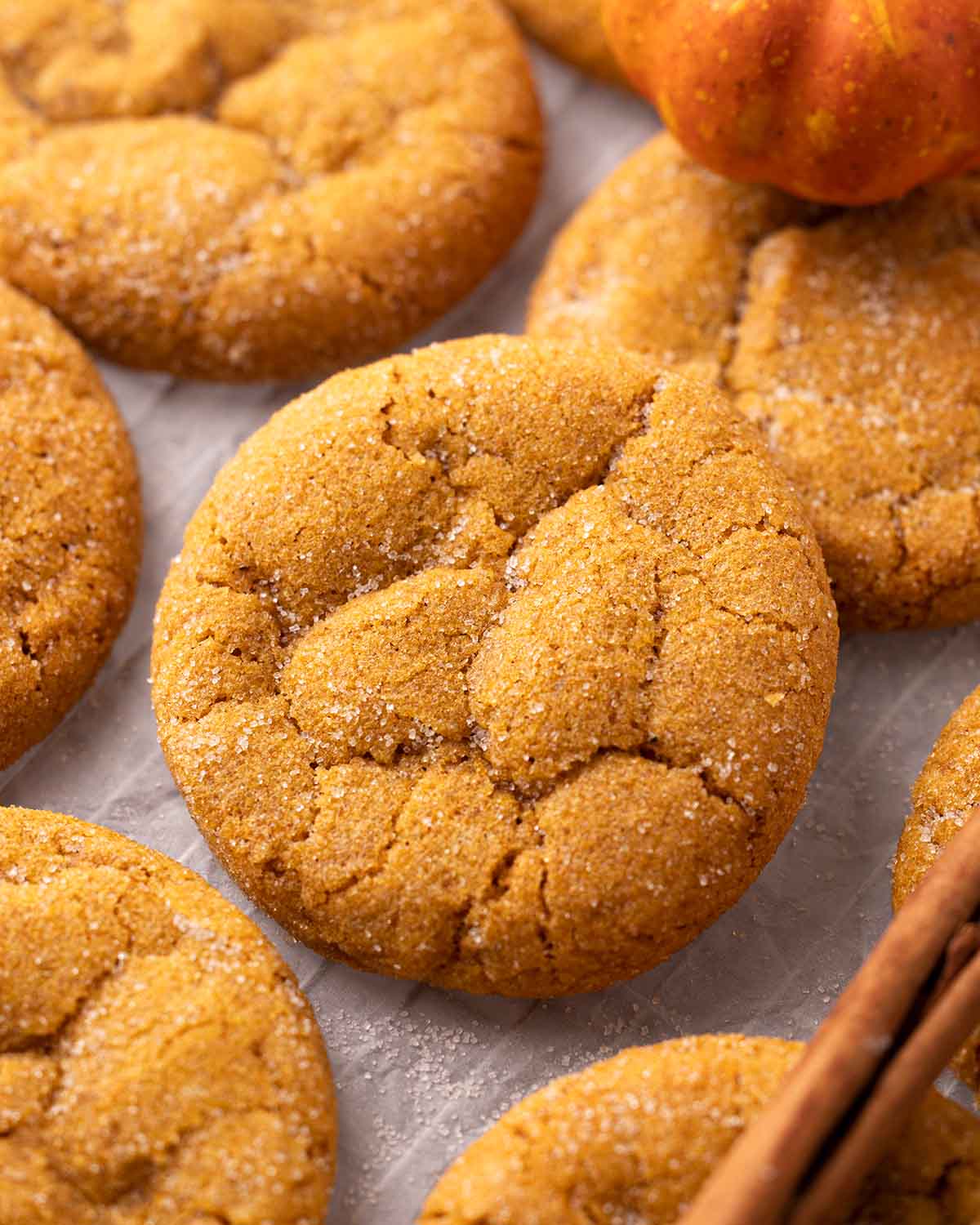 Close up of vegan pumpkin cookie amongst other cookies on parchment paper.