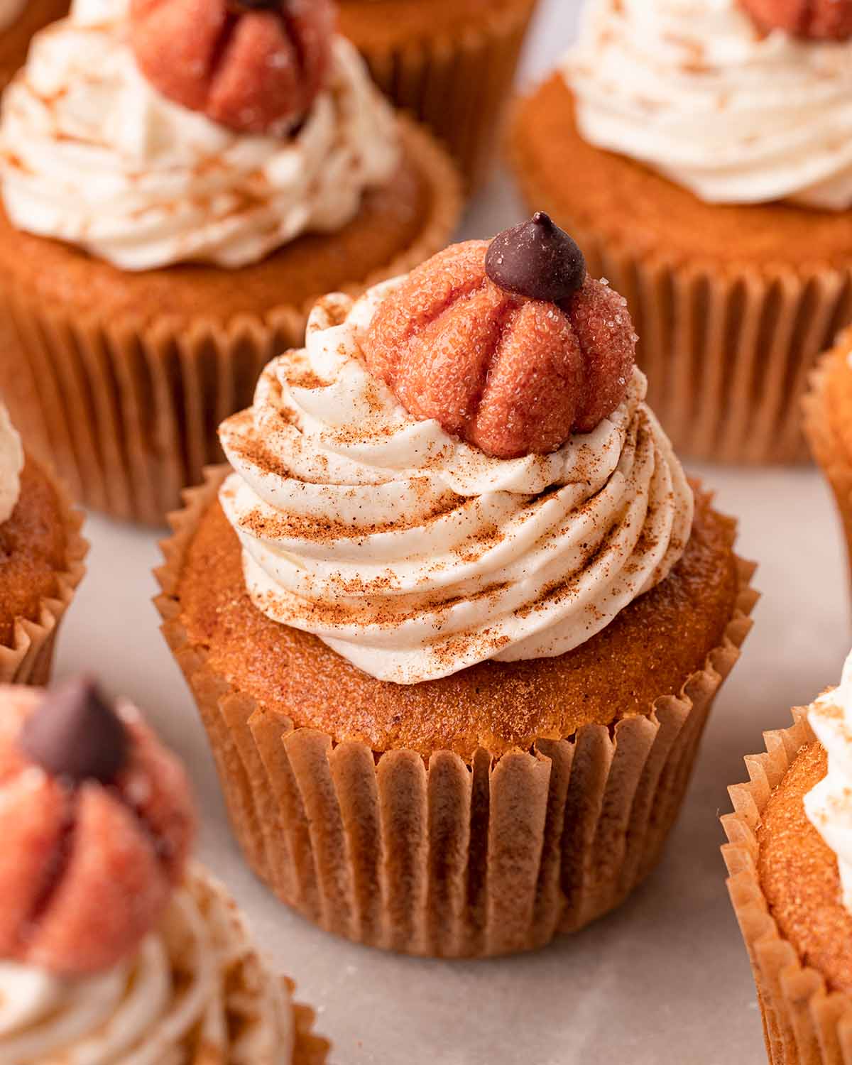 Close up of one pumpkin cupcake, focusing on cream cheese frosting and pumpkin decoration.