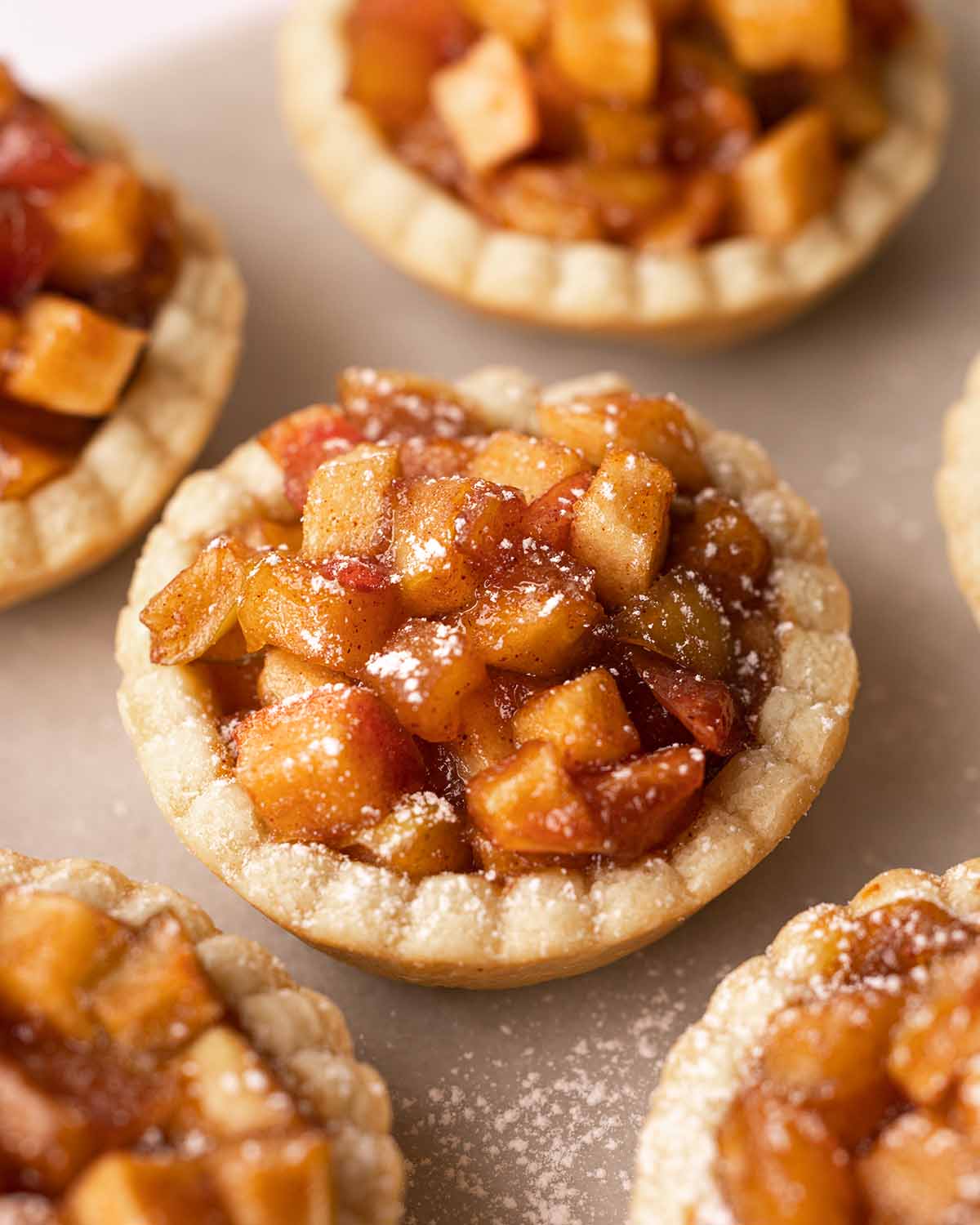 Close up of one tart focusing on the gooey golden brown apple filling.