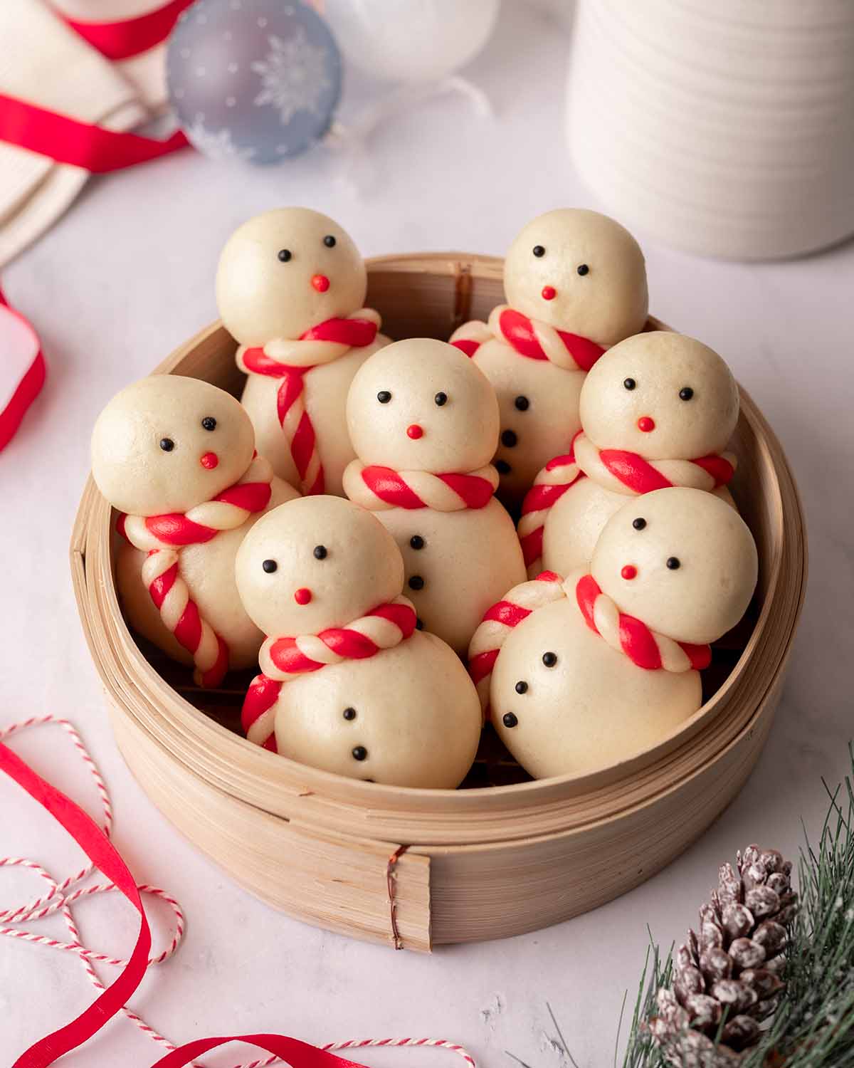 Seven steamed snowmen buns upright in a bamboo steamer.