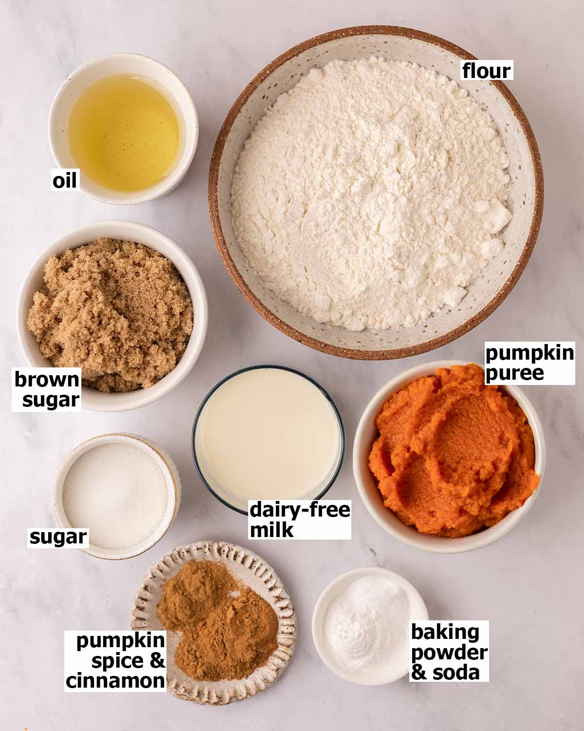 Flat-lay of ingredients in small dishes for pumpkin cake.