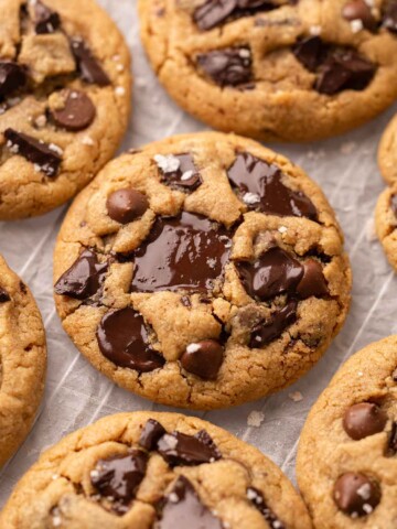 Close up of peanut butter cookies with melted chocolate chunks and chips, placed on on parchment paper.