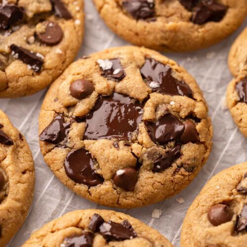 Close up of peanut butter cookies with melted chocolate chunks and chips, placed on on parchment paper.