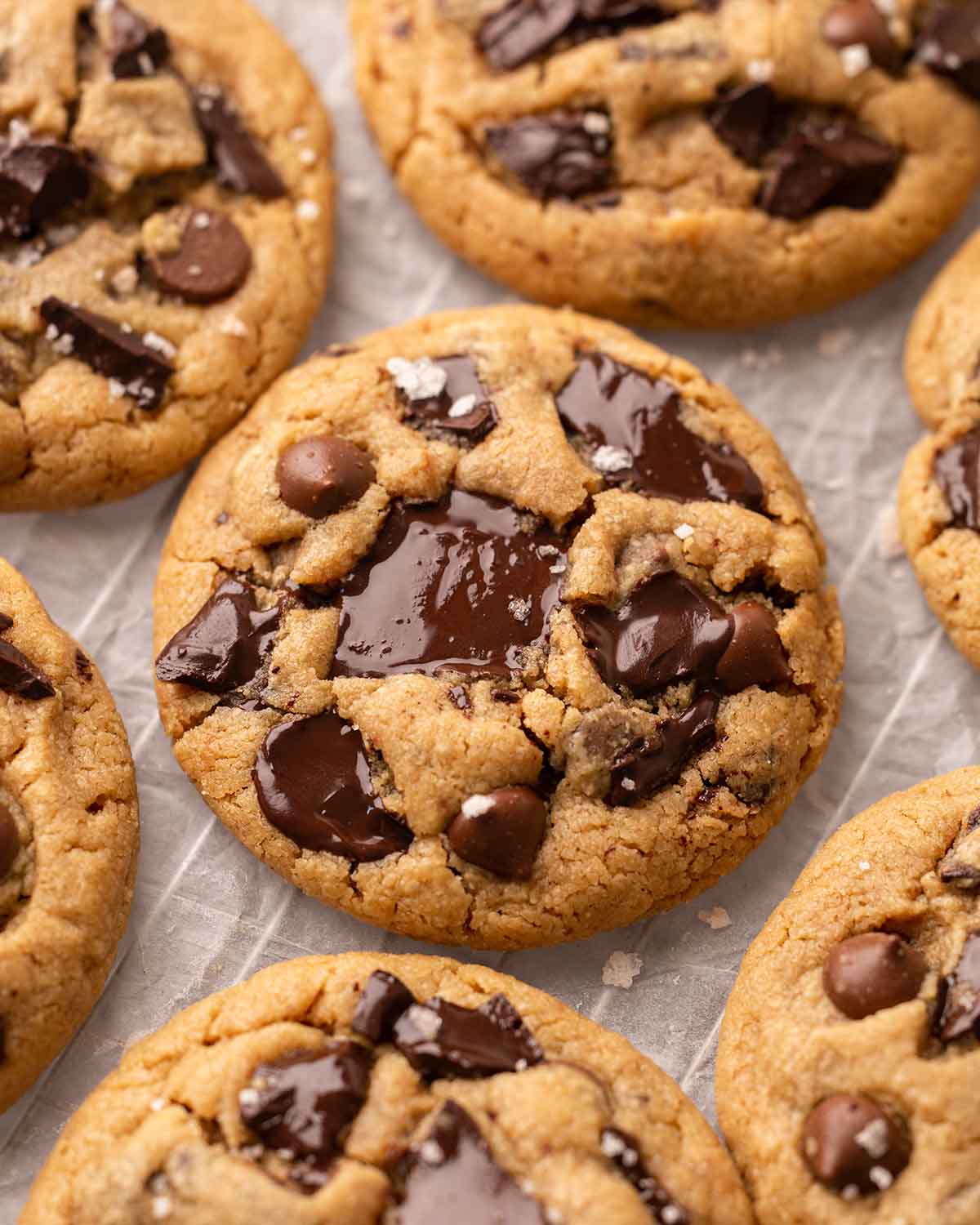 Close up of peanut butter cookies with melted chocolate chunks and chips, placed on on parchment paper.