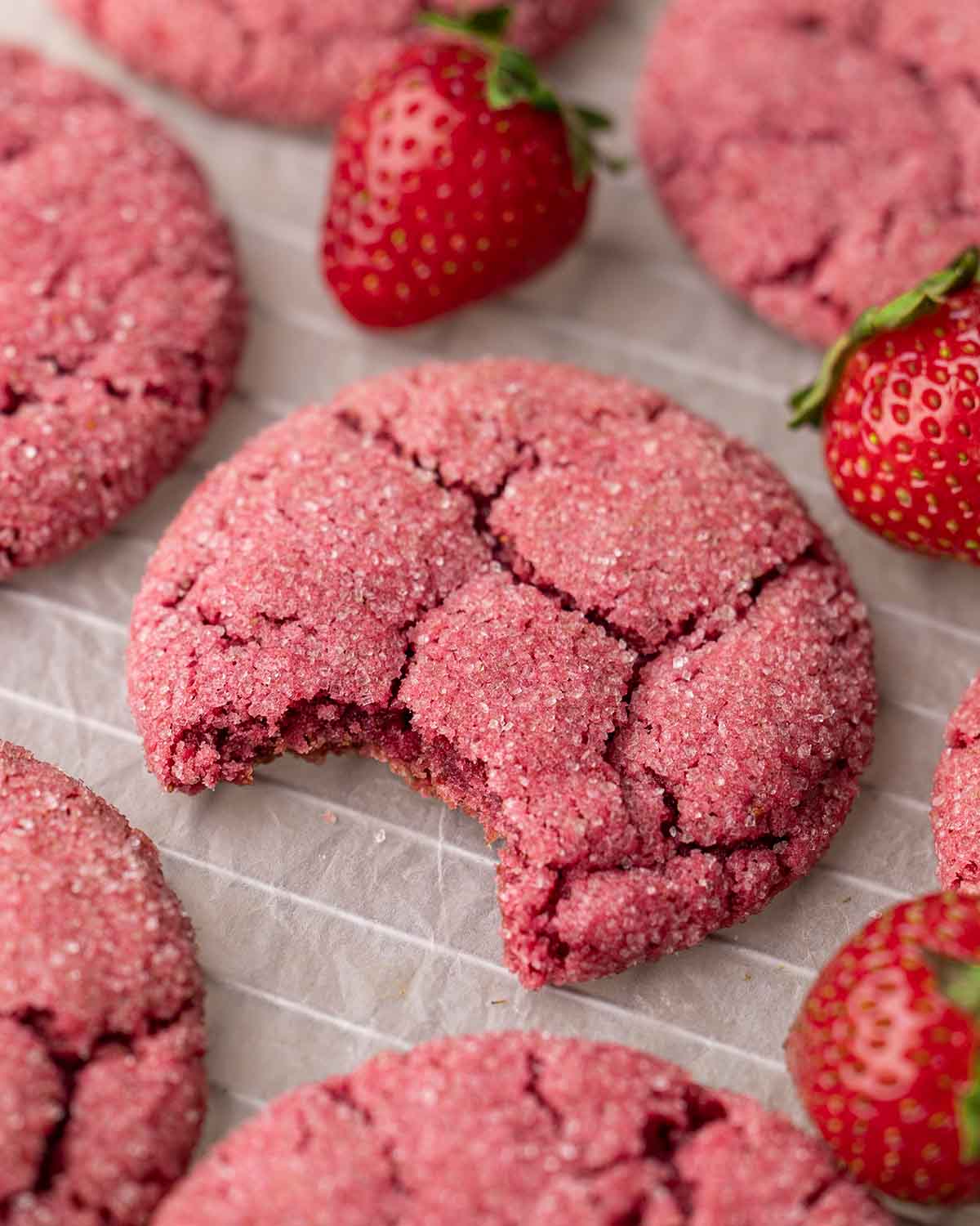 Close up of one strawbery cookie with bite taken out revealing chewy texture.