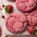 Close up of pink strawberry cookies with crackly sugar sugar on marble serving board.
