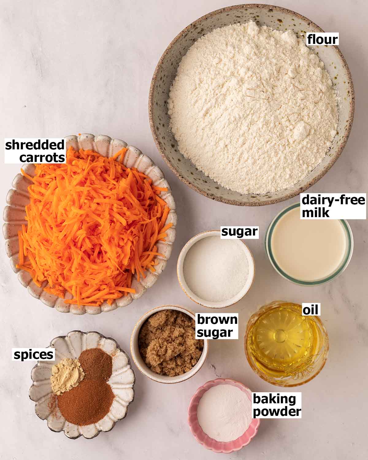 Flat-lay of ingredients in small dishes for the carrot cake loaf.