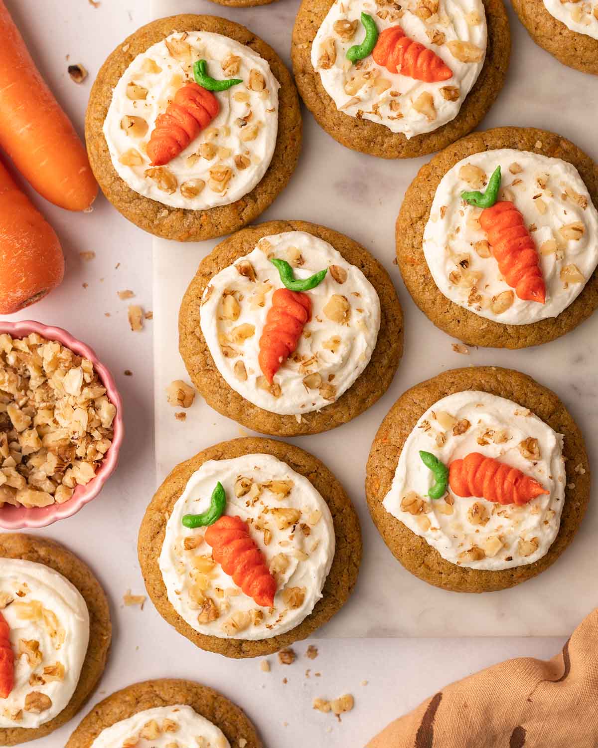 Flat-lay of decorated vegan carrot cake cookies on a marble serving board.