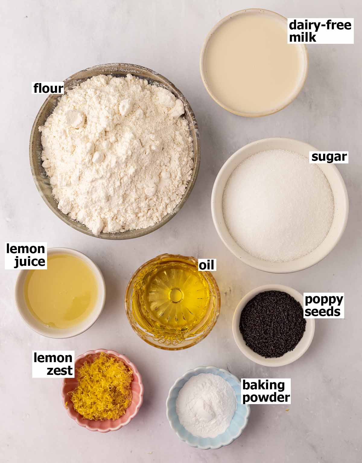 Flat-lay of ingredients in small dishes for lemon poppy seed cake.