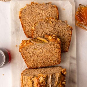 Banana bread on serving board, with 3 slices cut out and lying flat to show fluffy texture.