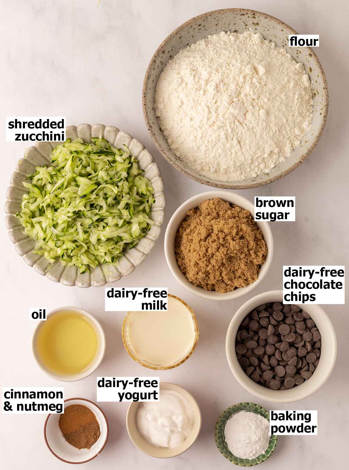 Flat-lay of ingredients in small dishes for vegan zucchini bread.