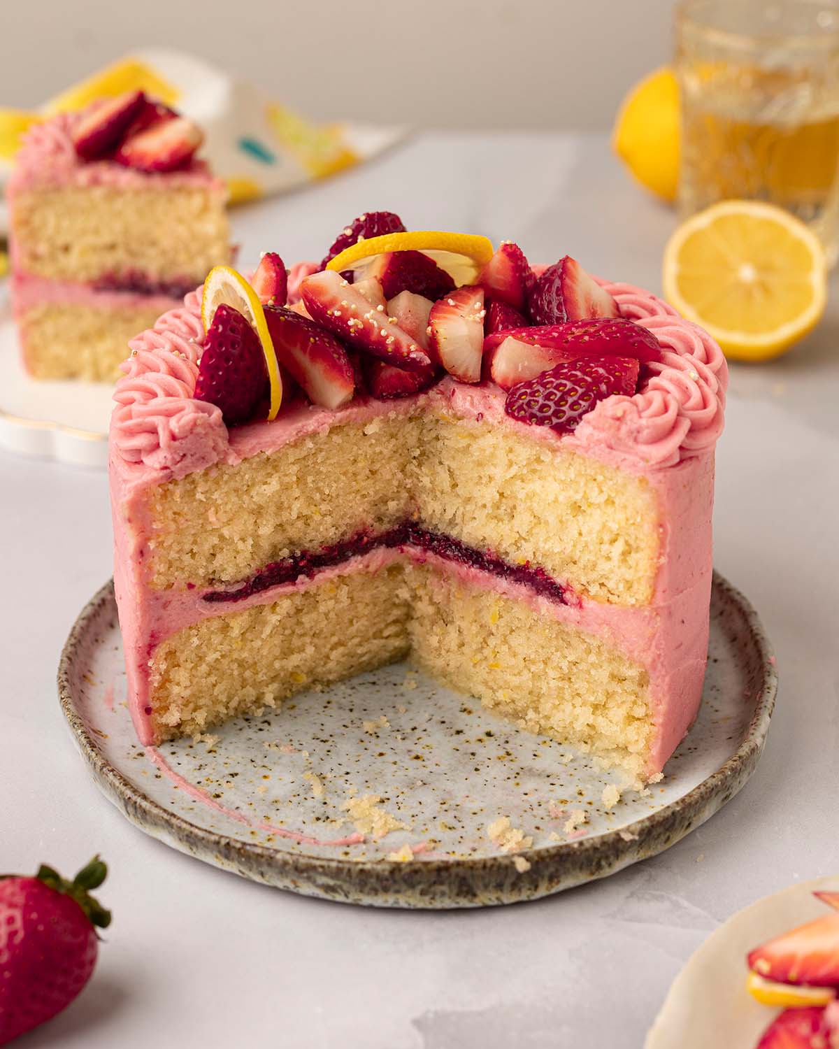 Small strawberry lemonade cake with a couple slices cut out revealing cross section of cake.