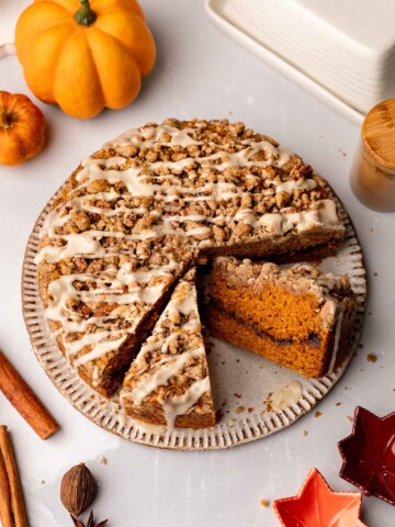 Vegan pumpkin coffee cake with two slices taken out revealing the cinnamon sugar layer in the middle of the cake.