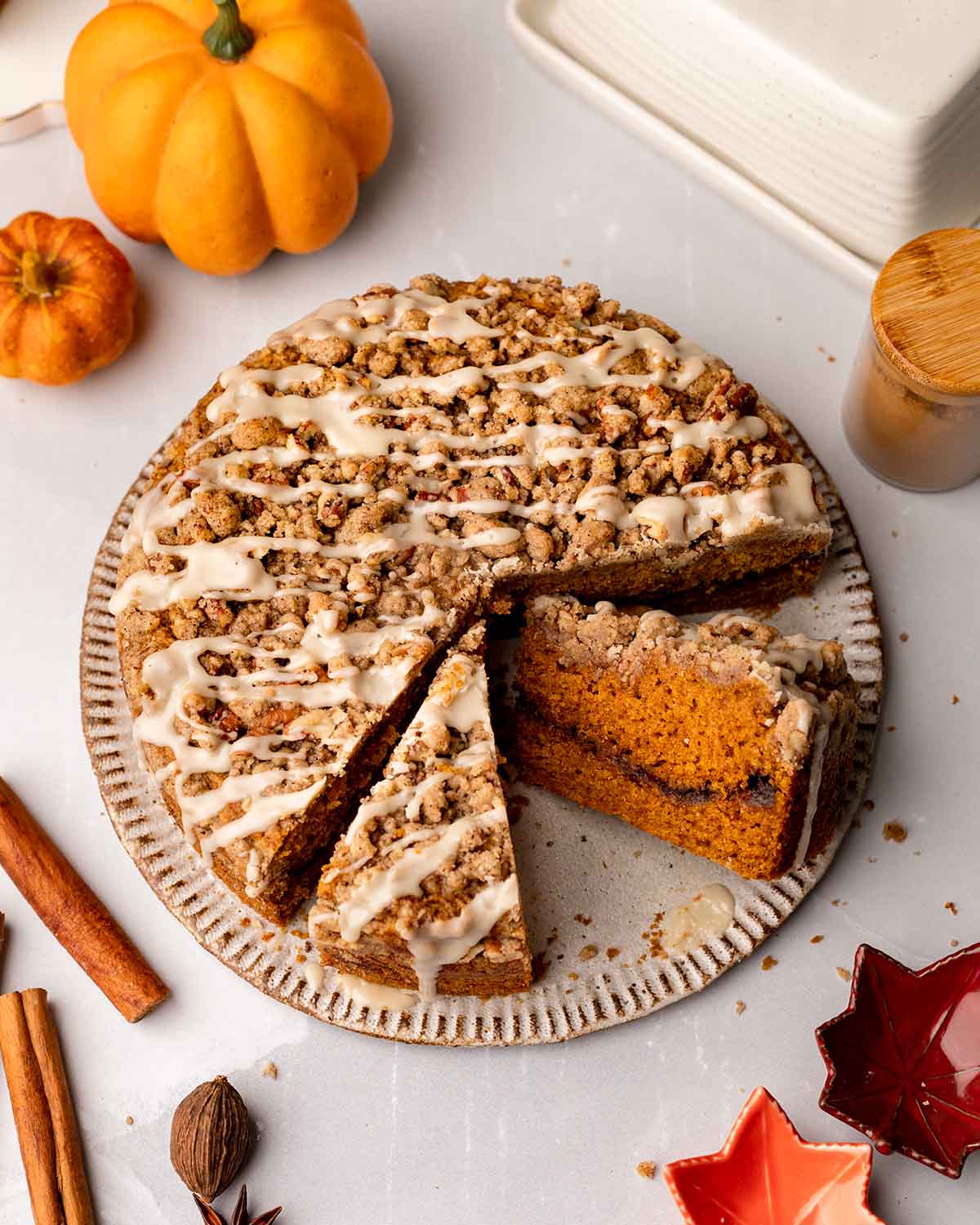 Vegan pumpkin coffee cake with two slices taken out revealing the cinnamon sugar layer in the middle of the cake.