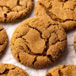 Close up of vegan ginger cookie on wire rack with more cookies in background.