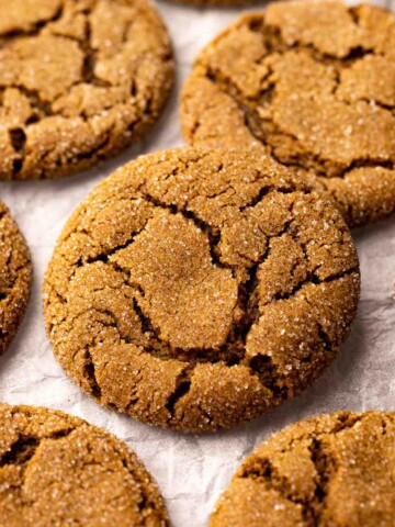 Close up of vegan ginger cookie on wire rack with more cookies in background.