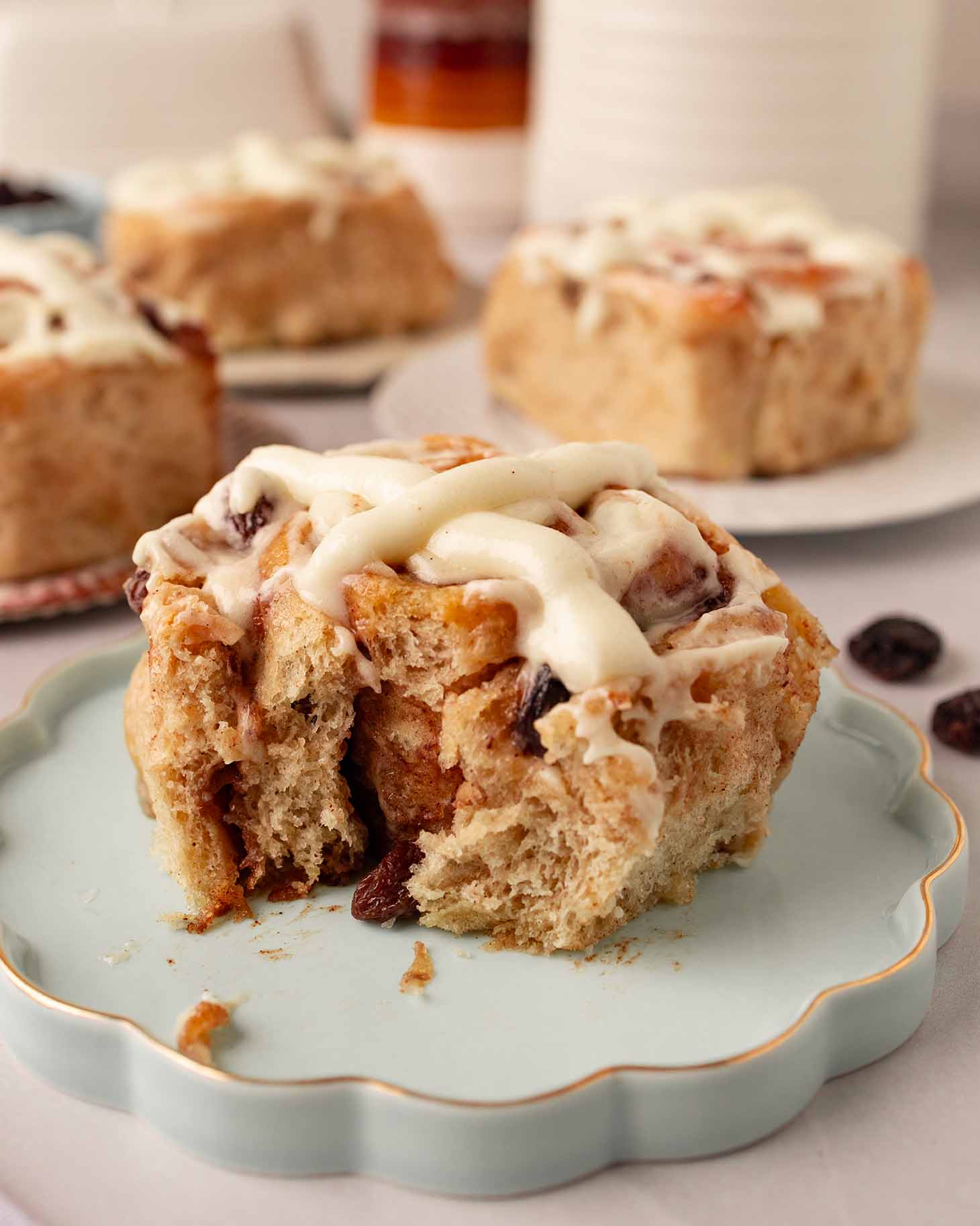 Close up of hot cross cinnamon roll with bite taken out revealing soft fluffy texture.