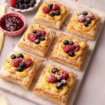 Puff pastry squares filled with custard and topped with fresh berries on a serving platter.