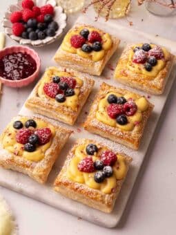 Puff pastry squares filled with custard and topped with fresh berries on a serving platter.