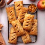 Apple hand pies stacked a small lined baking pan.