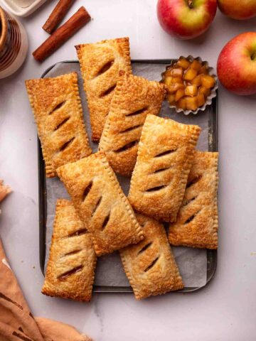 Apple hand pies stacked a small lined baking pan.