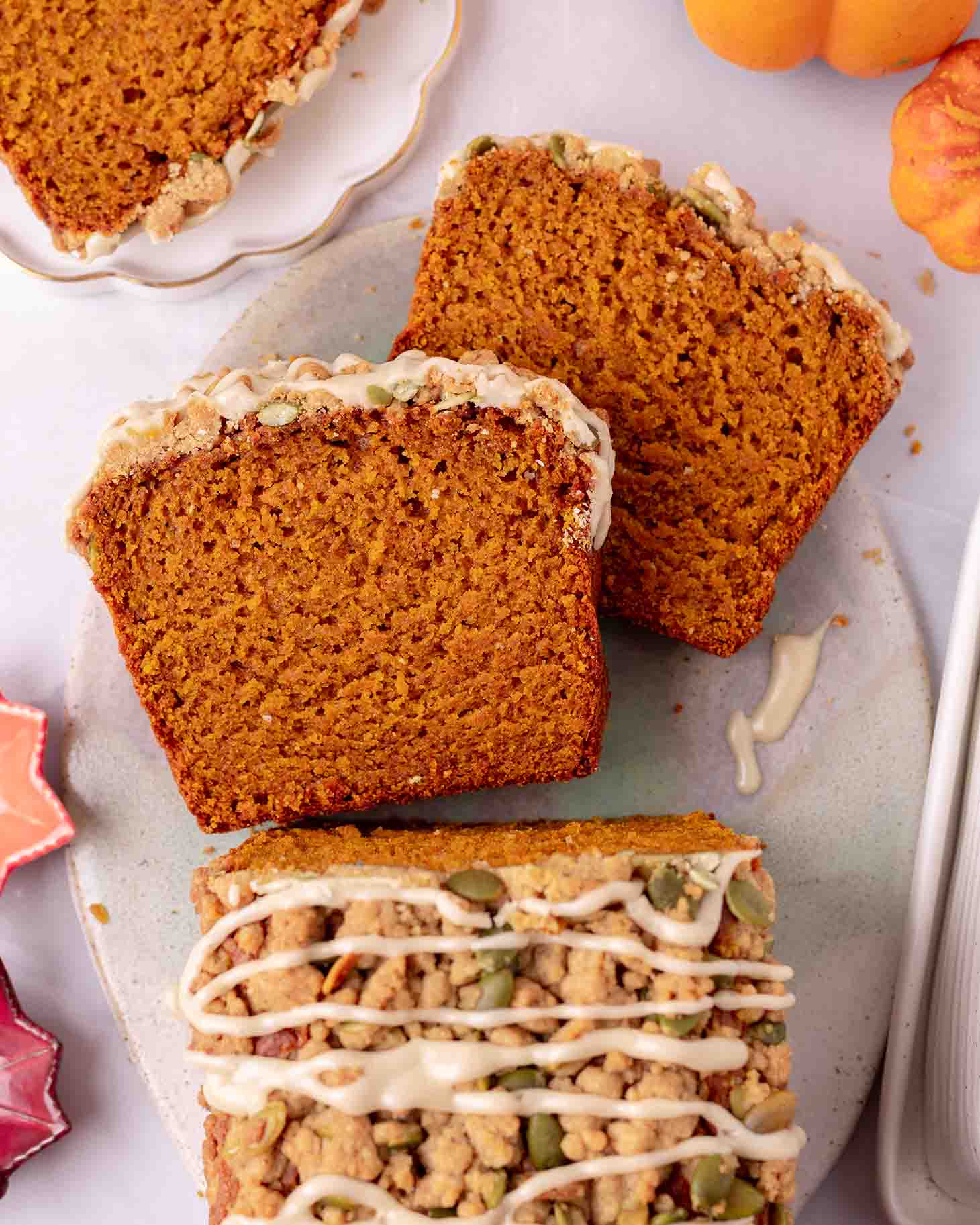 Vegan pumpkin bread on platter with two slices cut out showing fluffy golden texture.