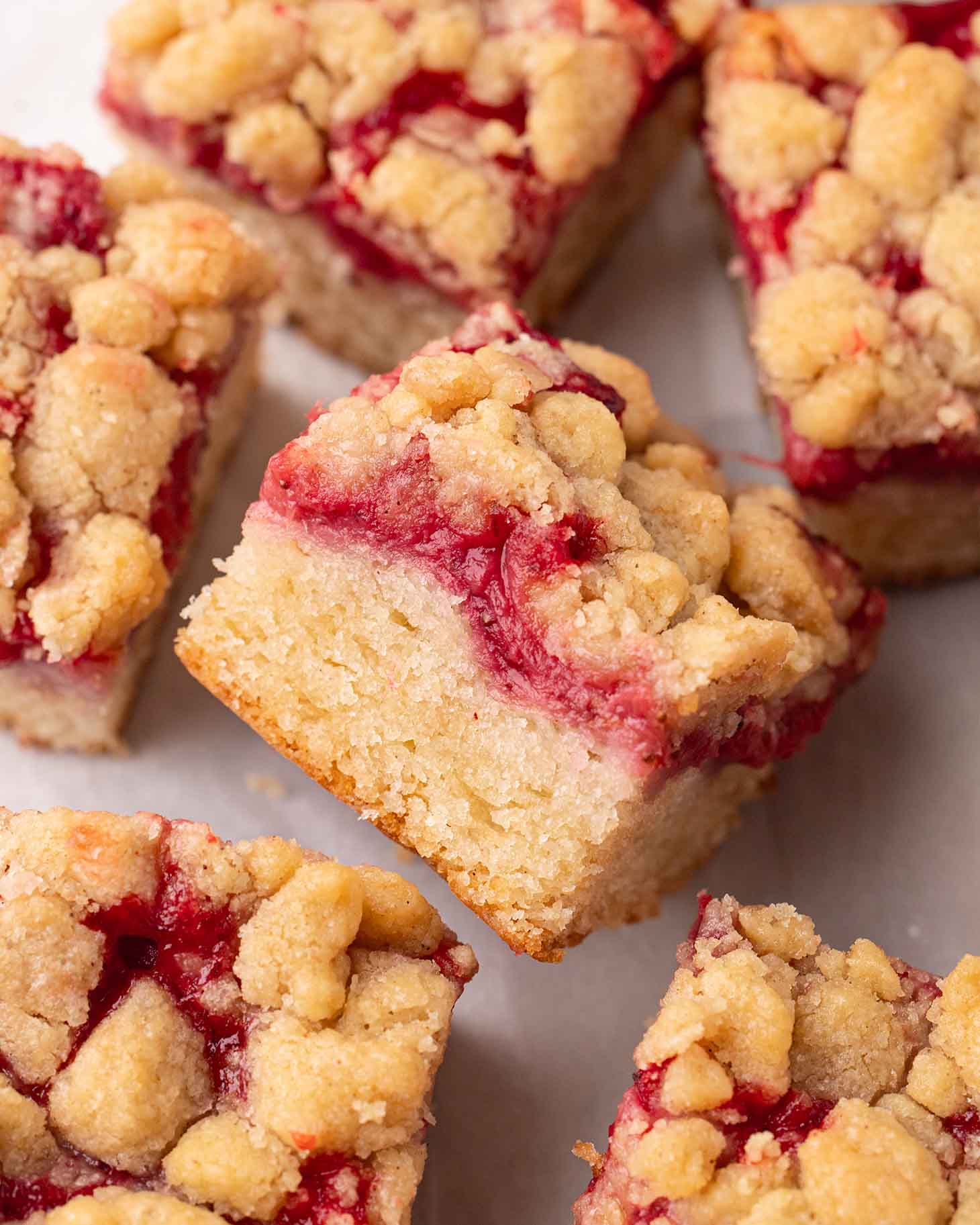 Close up of one strawberry crumb cake focusing on red jammy layer.