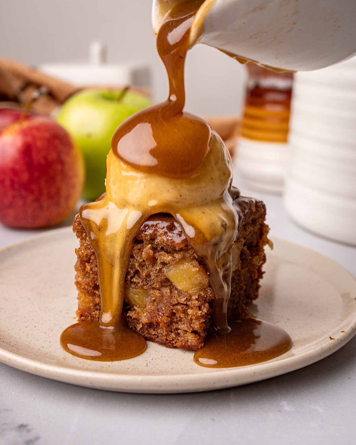One square of toffee pudding with ice cream and toffee sauce poured on top.