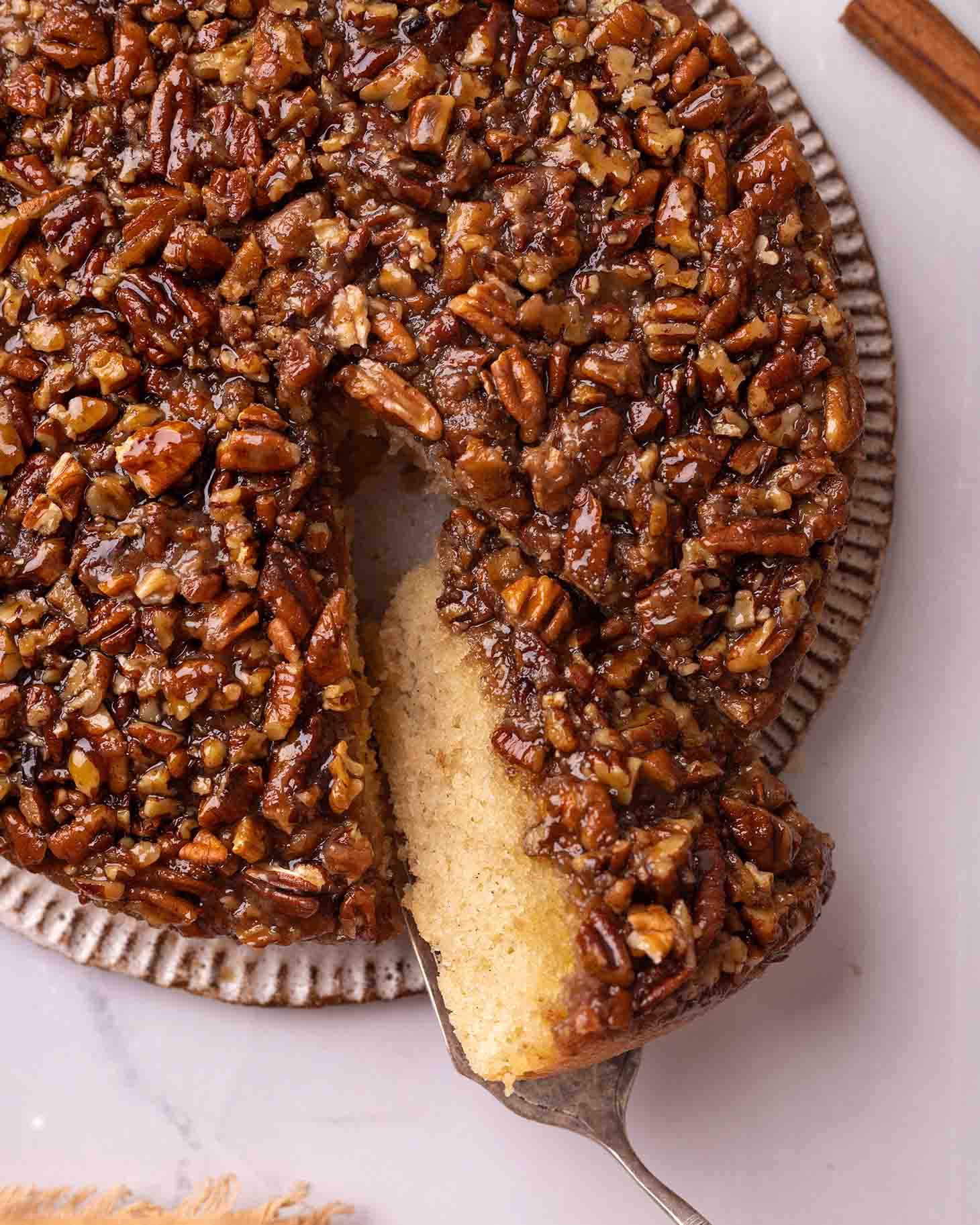 Overhead close up of pecan cake with one slice cut out revealing texture.