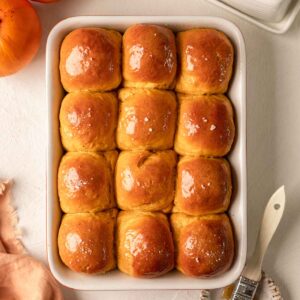 Dozen of golden pumpkin buns in baking tray.