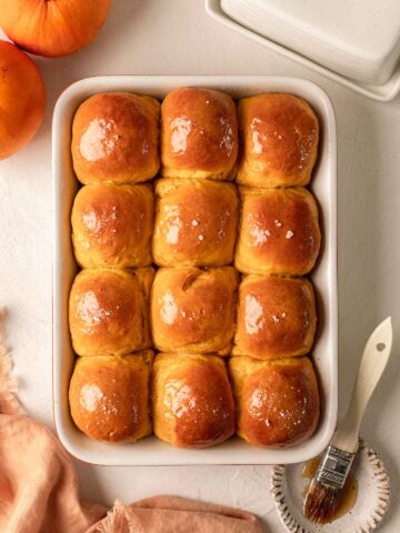 Dozen of golden pumpkin buns in baking tray.