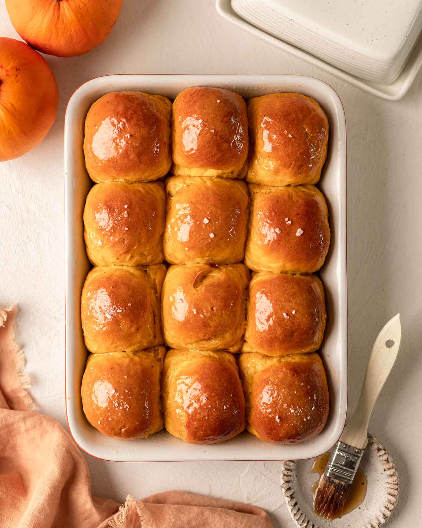 Dozen of golden pumpkin buns in baking tray.