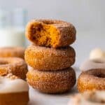 Stack of sugar coated and thick donuts showing golden orange and fluffy interior.