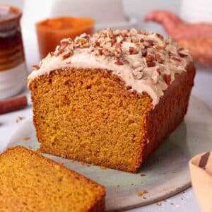 Sweet potato bread on a serving platter with one slice cut off revealing soft and moist texture of the bread.