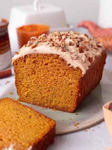 Sweet potato bread on a serving platter with one slice cut off revealing soft and moist texture of the bread.