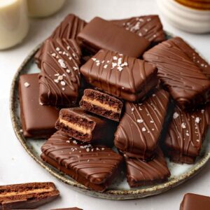 Plate of homemade vegan Tim Tams with one Tim Tam cut revealing cross section.