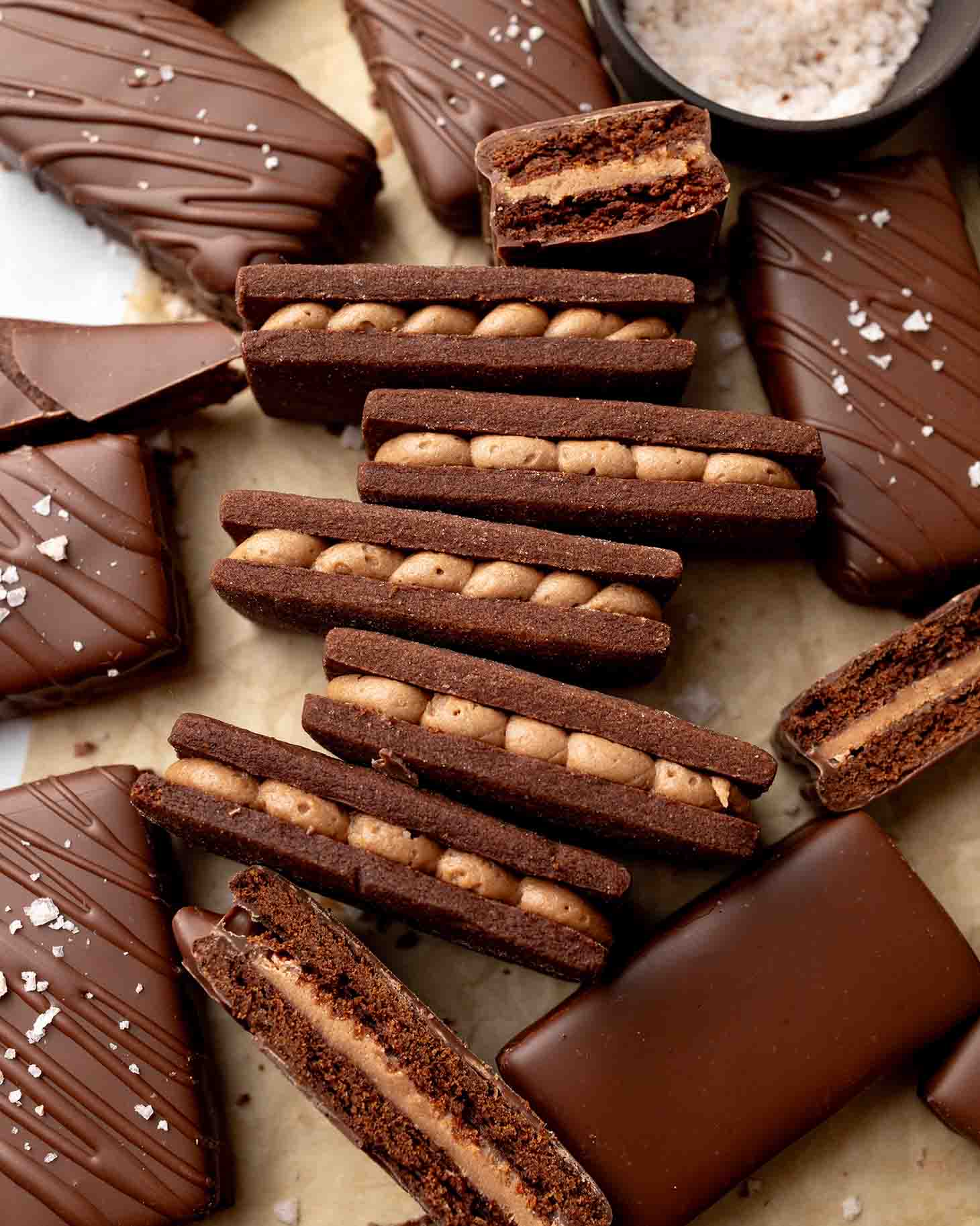 Flat-lay of several uncoated vegan Tim Tams amongst Tim Tams coated in chocolate.