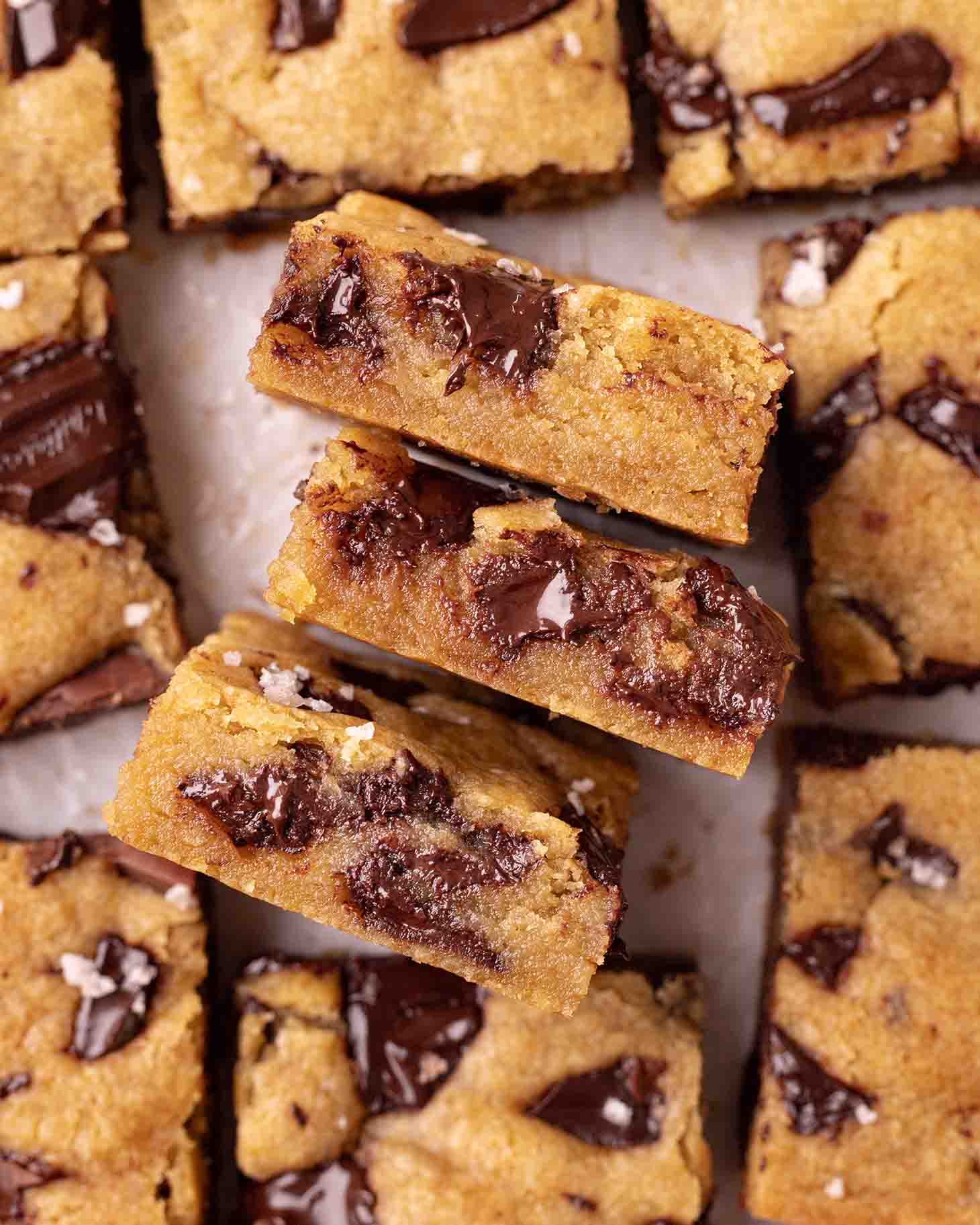 Close up of the gooey texture of three chocolate chip cookie bars.