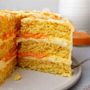 Slice of three-layered orange cake revealing fluffy cake layers, orange-flavored buttercream and orange curd.