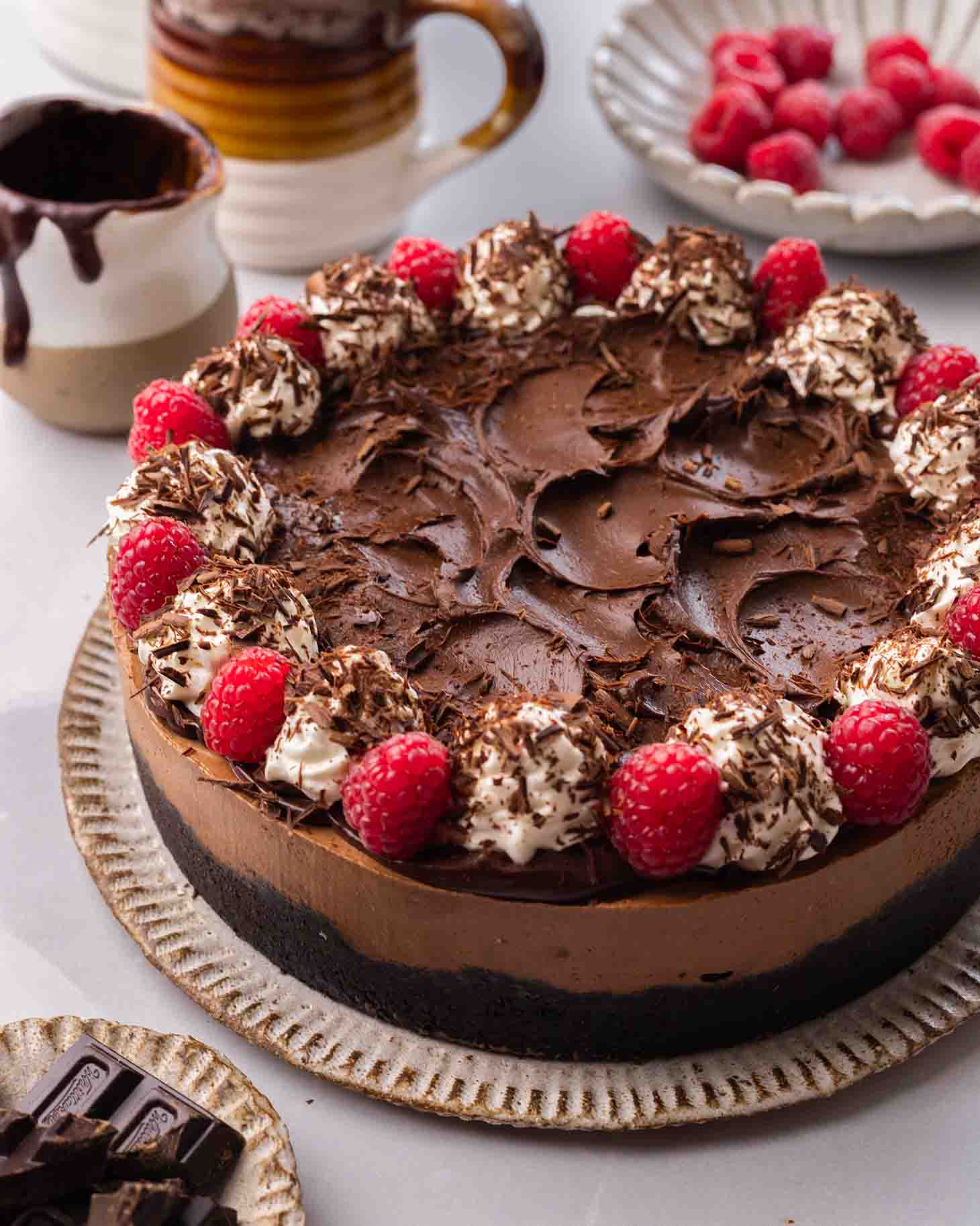 Chocolate cheesecake topped with chocolate ganache, whipped cream, chocolate shavings and raspberries.