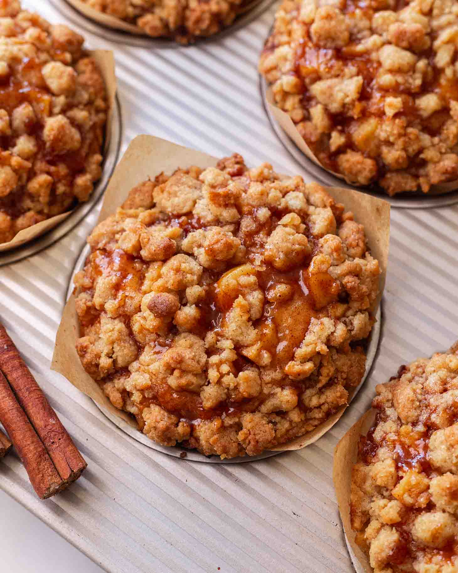 Close up of a muffin top focusing on the gooey apples and golden crumble.