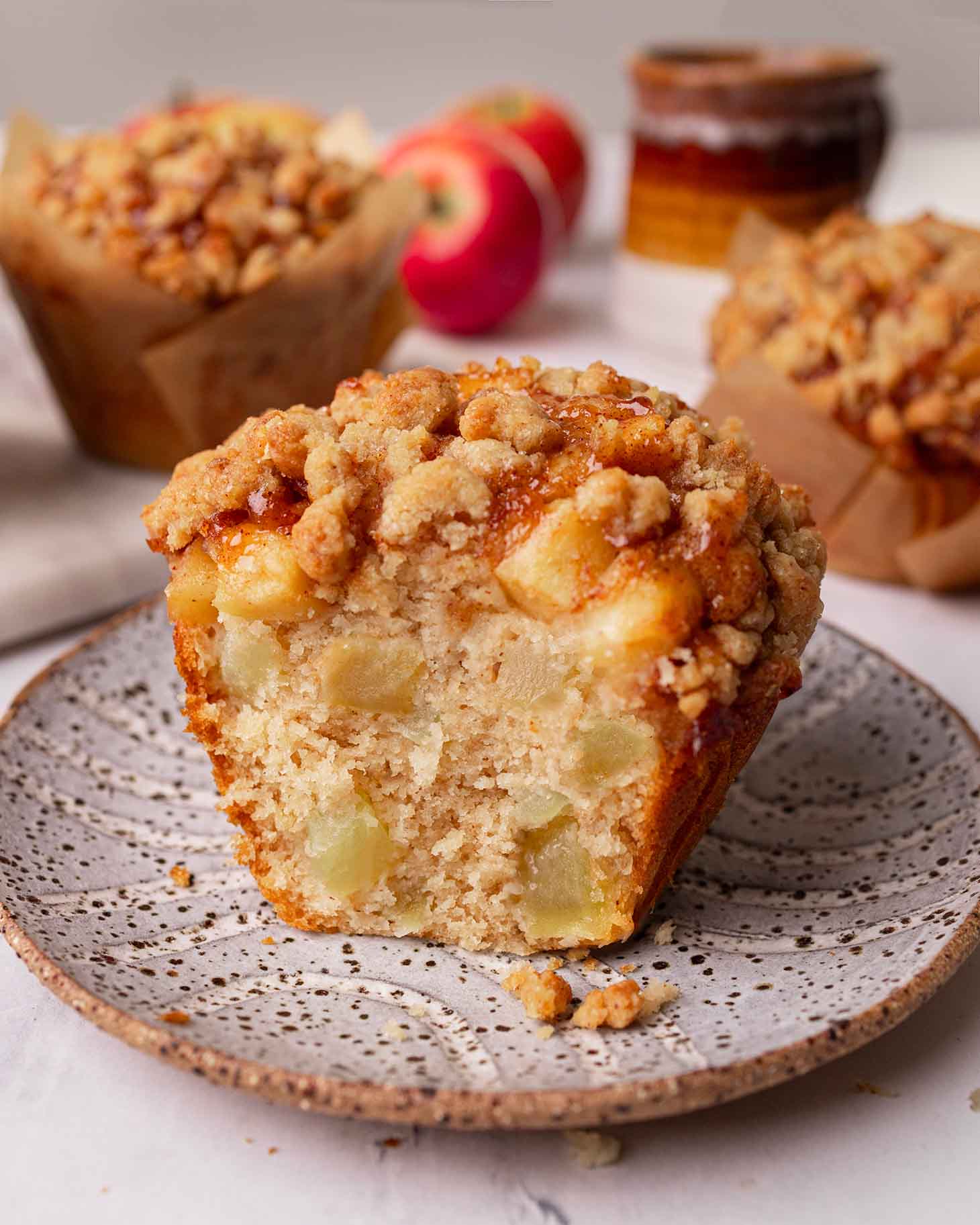 Close up of a muffin with a bite taken out showing golden texture and lots of apple pieces.