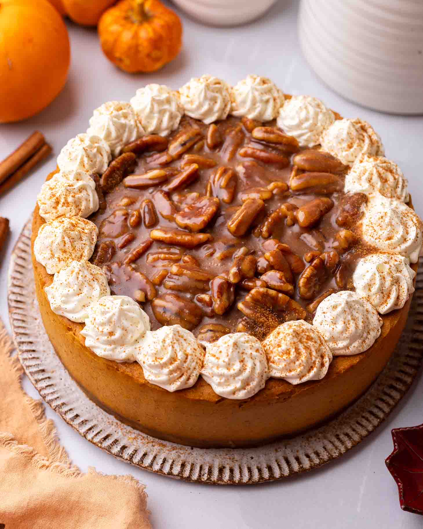Overhead image of pumpkin cheesecake focusing on gooey pecan caramel topping and whipped cream decorative border.